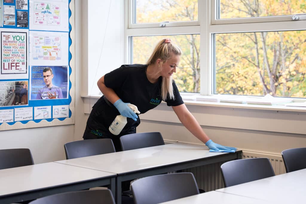 Female cleaner cleaning school desk